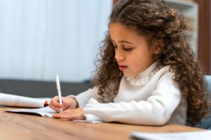 menina aprendendo a escrever e desenvolvendo sua coordenação motora fina